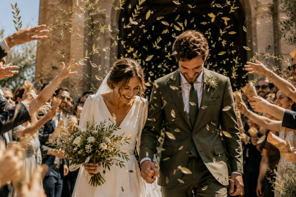 Novios saliendo de la ceremonia entre hojas de olivo
